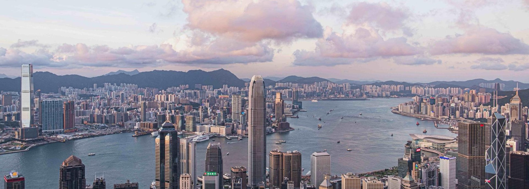 Victoria Harbour and the Hong Kong skyline at dusk, under pink clouds